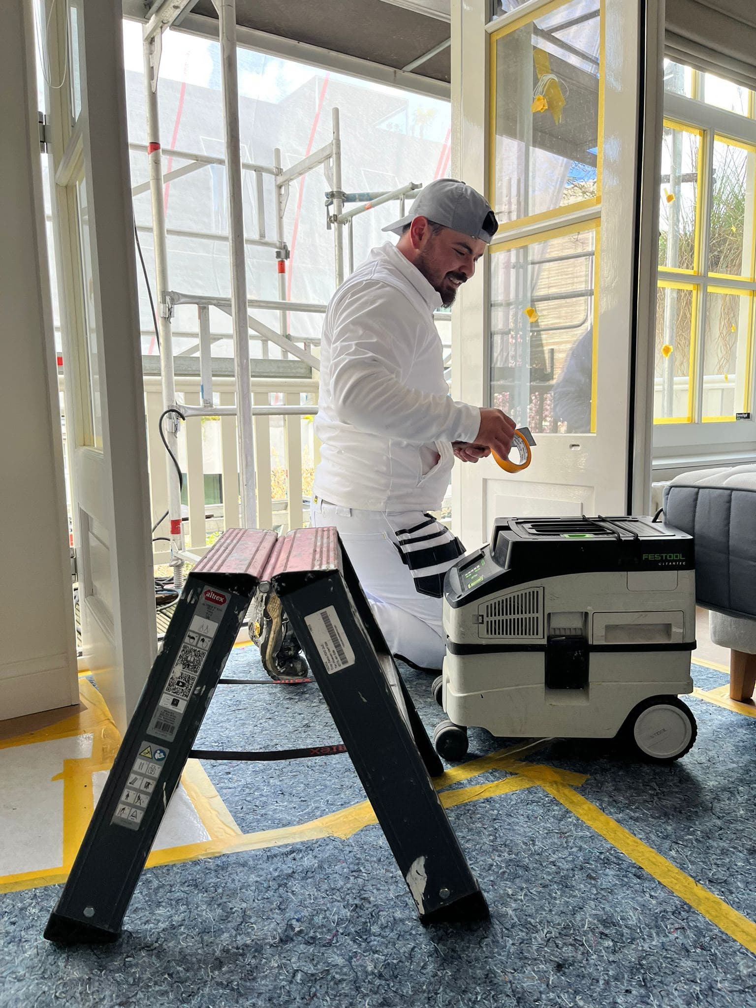 Aytun van IT Klussenbedrijf op zijn knieën aan het werk met gereedschap