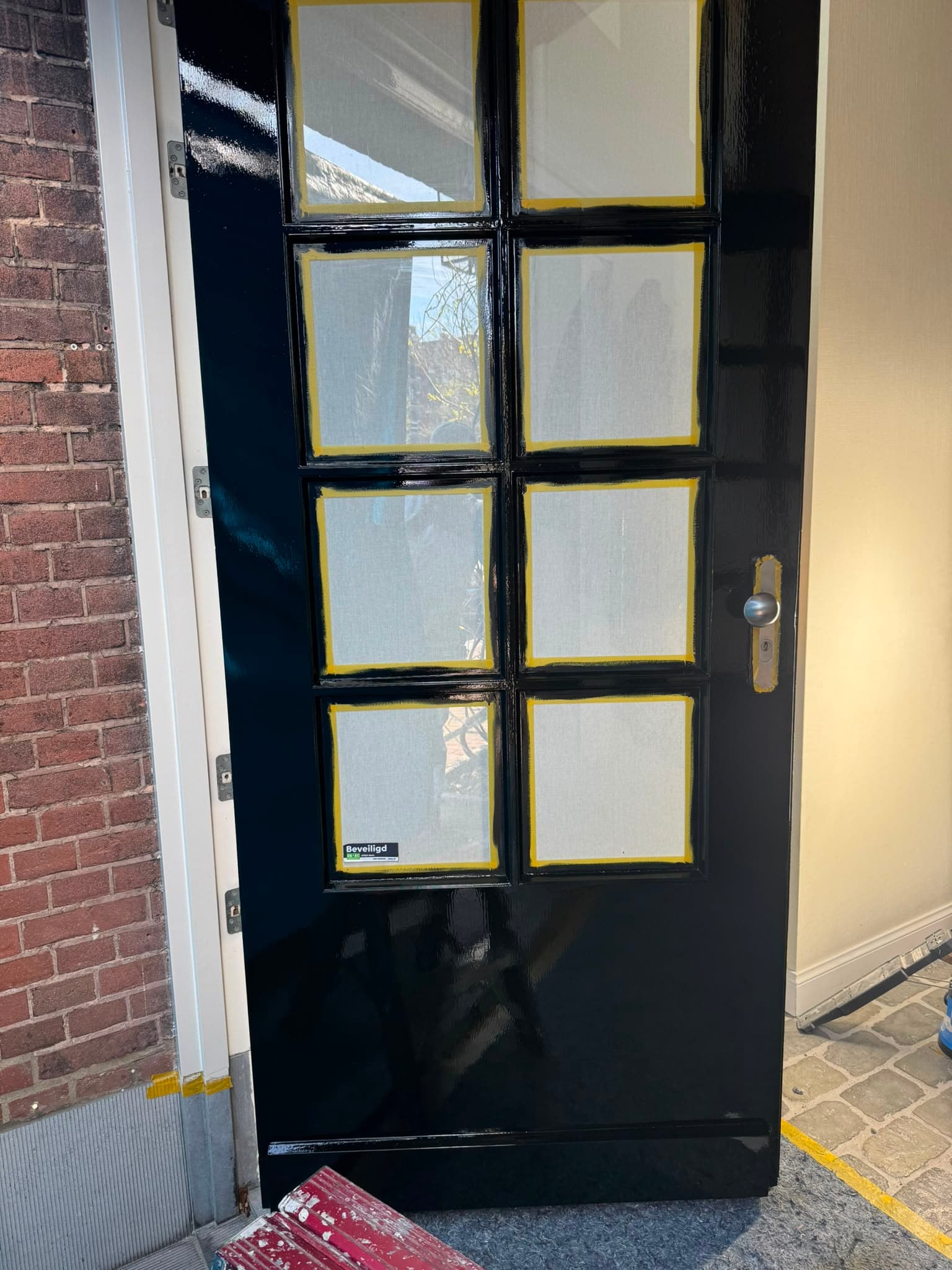 Deur met zorgvuldig afgeplakt glas tijdens het lakwerk